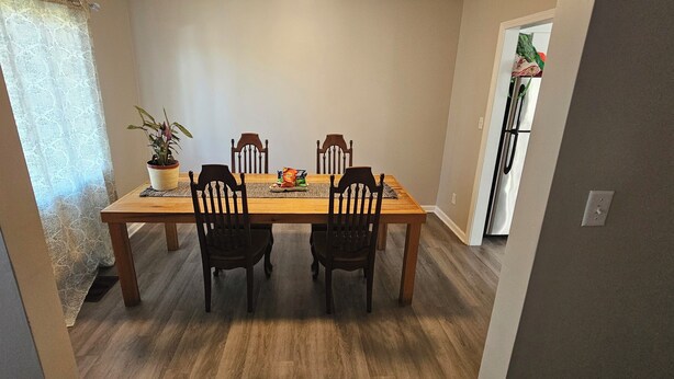 A dining room with a wooden table and four chairs, a potted plant, and a bag of chips on the table. - Home Away From Home!!! (Birmingham)