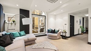 A modern living room with a sofa, armchairs, and a coffee table. There is a large window with a view of a brick building. - Mayfair 3bedr-3batr. 1,405sq/ft balcony A/C (London)