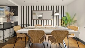 A modern dining area with a white table, wicker chairs, and a black and white striped wall. - Mayfair 3bedr-3batr. 1,405sq/ft balcony A/C (London)