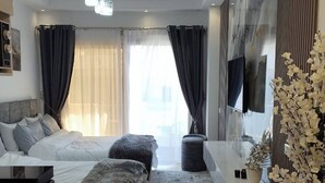 Una habitación de hotel moderna con una cama grande, un sofá, un escritorio, una lavadora y un televisor.