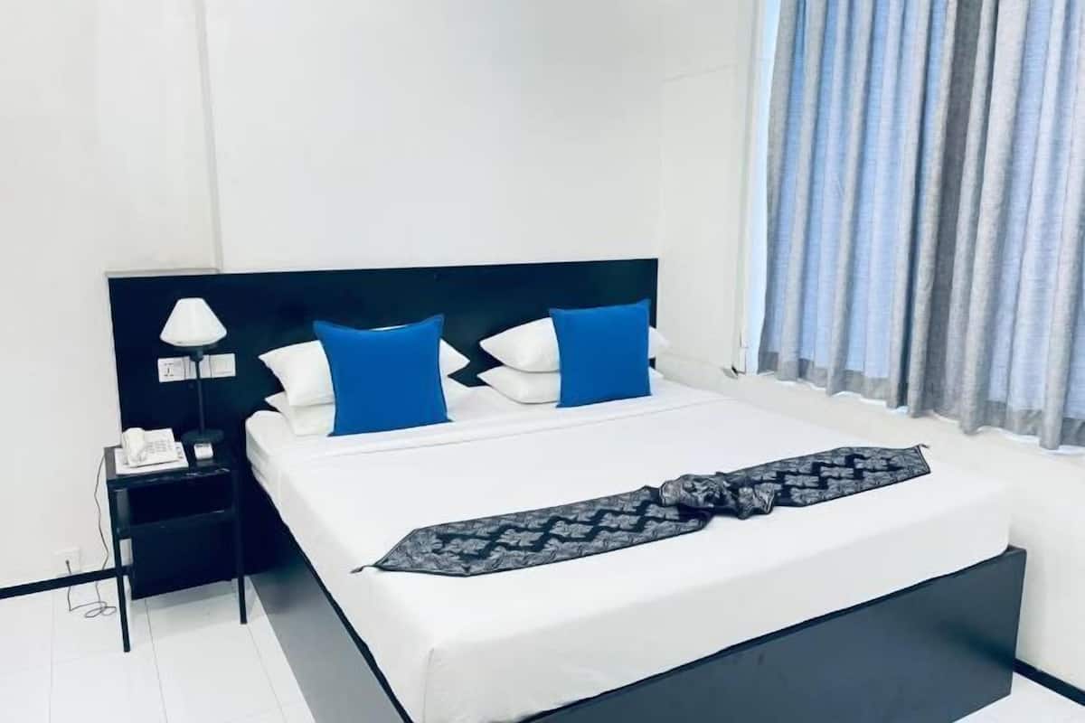 A hotel room with a bed, a nightstand with a lamp, and a window with curtains.