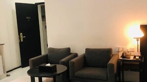 A room with two armchairs, a small table with a box, a lamp on a side table, and a door with the number 603. - Yama Hotel & Rooftop Bar (Botataung)