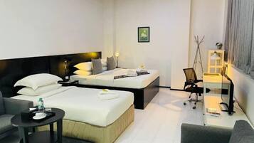 A modern hotel room with two beds, a desk, a chair, and a small table.