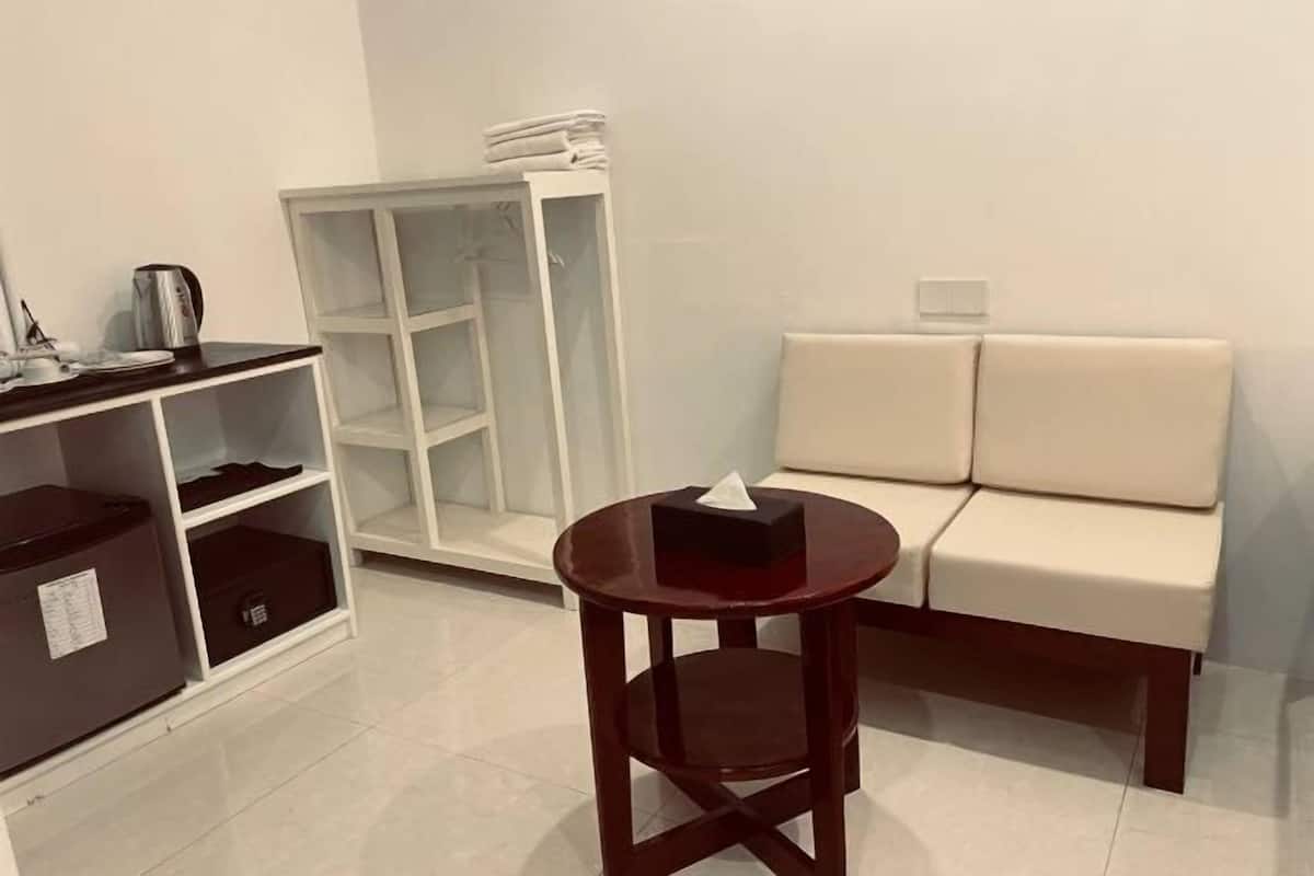 A room with a white sofa, a small wooden table, a white cabinet, and a white wardrobe.