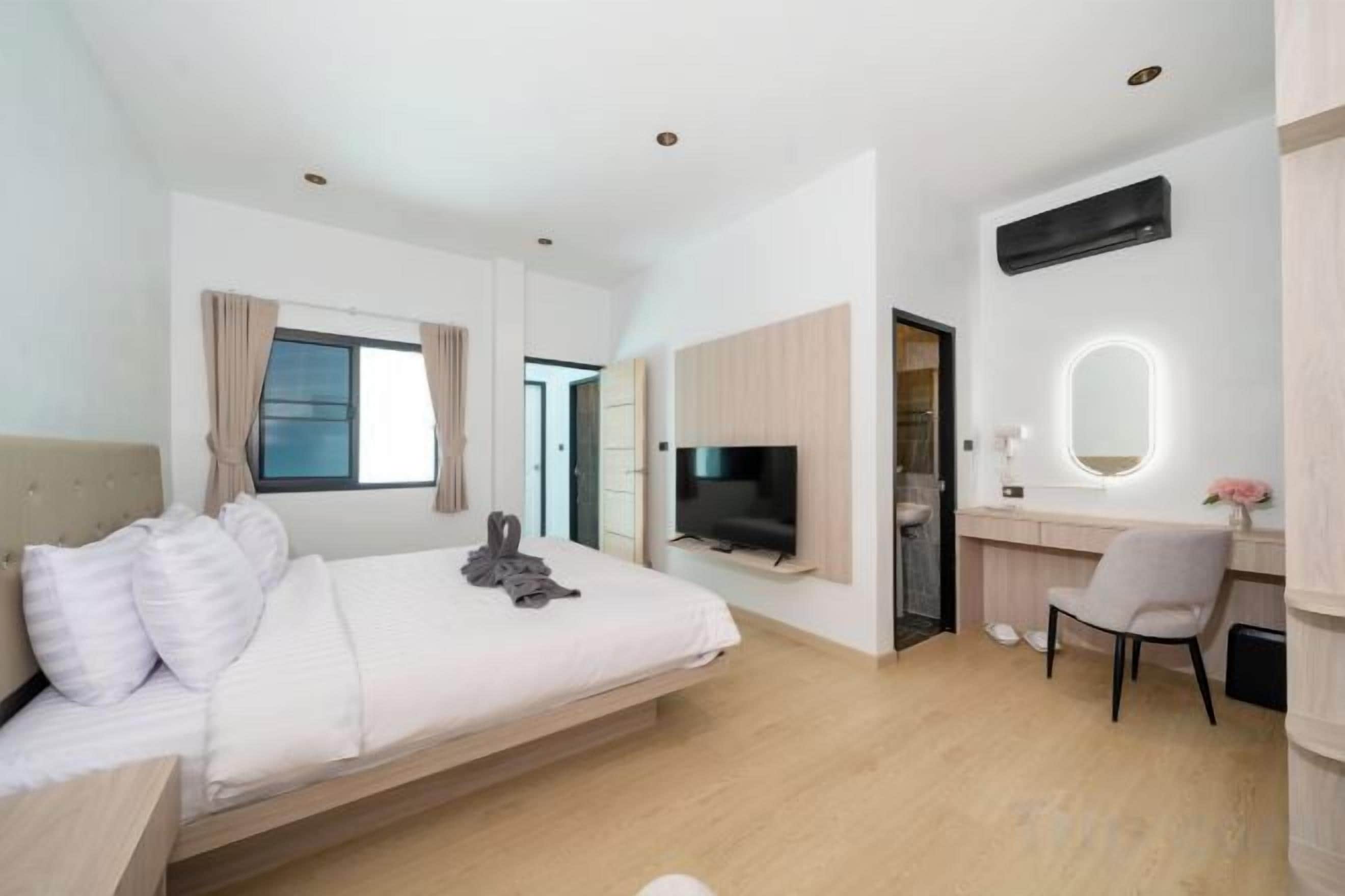 A modern hotel room with a bed, a desk, a TV, and a bathroom.