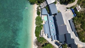 Vista aerea di un hotel costiero con diversi edifici, una spiaggia e una barca.
