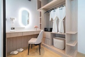 A modern bathroom with a vanity, a mirror, a robe rack, and a basket. - The Hideout Beachfront (Phuket)