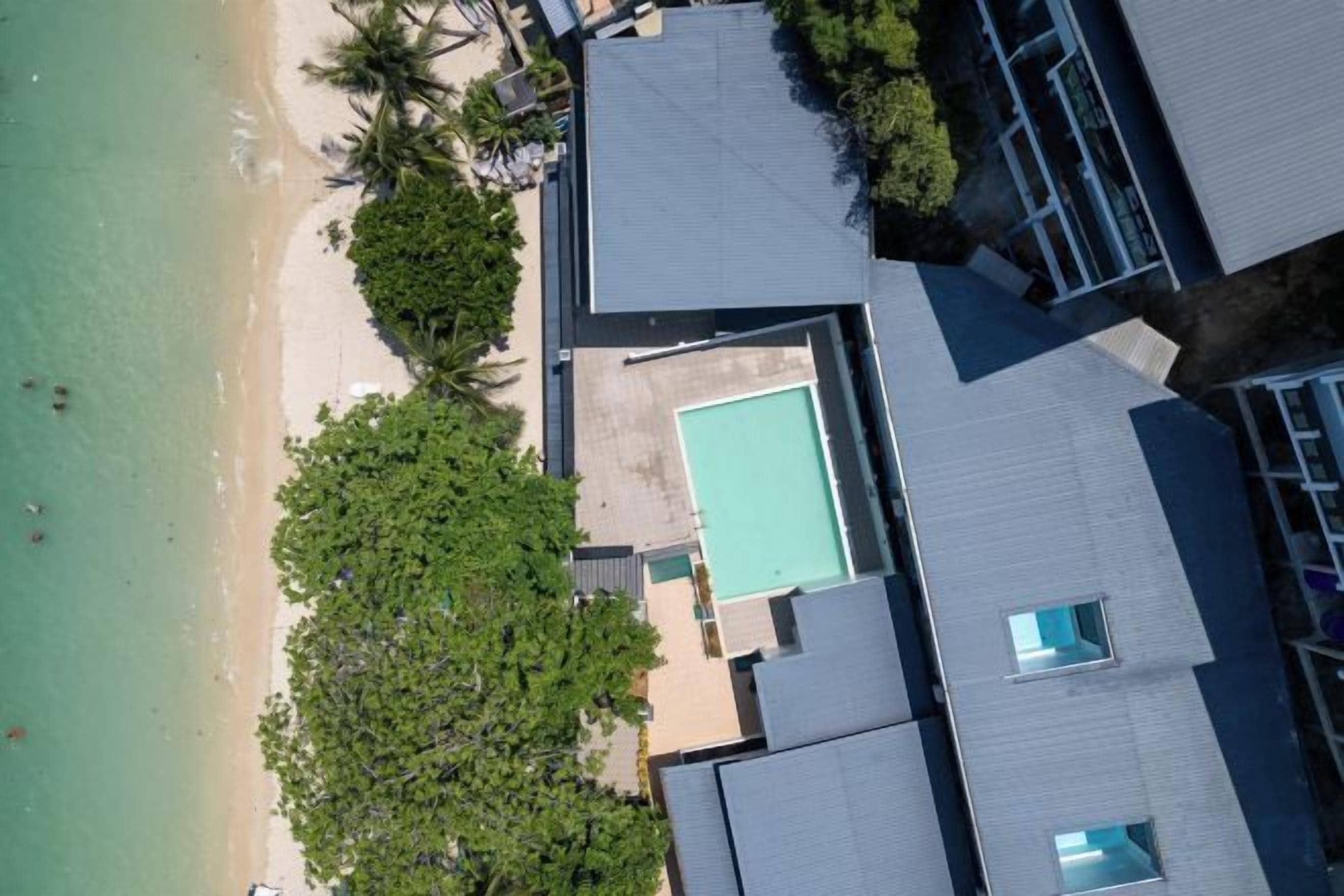 A resort with a swimming pool, beach, and palm trees.