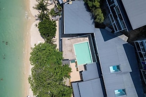 A resort with a swimming pool, beach, and palm trees. - The Hideout Beachfront (Phuket)