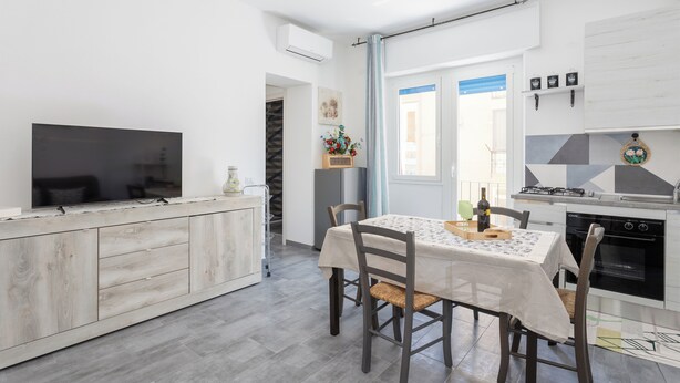 Eine moderne Küche mit Essbereich, ausgestattet mit Backofen, Fernseher und Esstisch mit Stühlen.