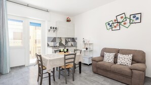 Ein modernes Wohnzimmer mit Essbereich, einer Couch mit gemusterten Kissen und einem an der Wand befestigten Bilderrahmen.