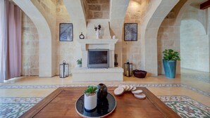 Un salon spacieux doté d’une cheminée, de murs en pierre et d’une table basse en bois agrémentée d’objets décoratifs.