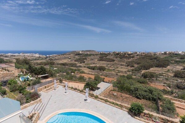 A pool area with a view of the surrounding landscape and distant buildings. - Property with Pool access - Xaghra near Marsalforn (Xagħra)