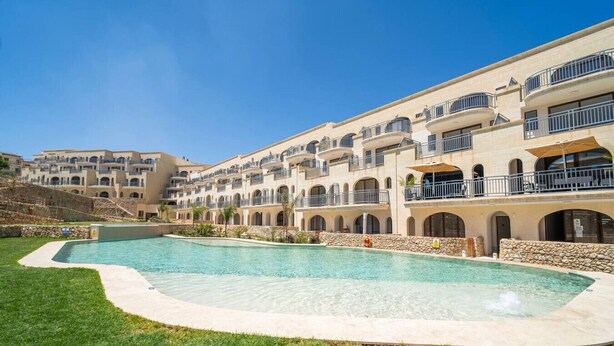 Un hôtel doté de nombreux balcons, d’une piscine et d’un mur en pierre.