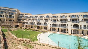 Un hôtel doté de nombreux balcons, d’une piscine et d’une cour aménagée.