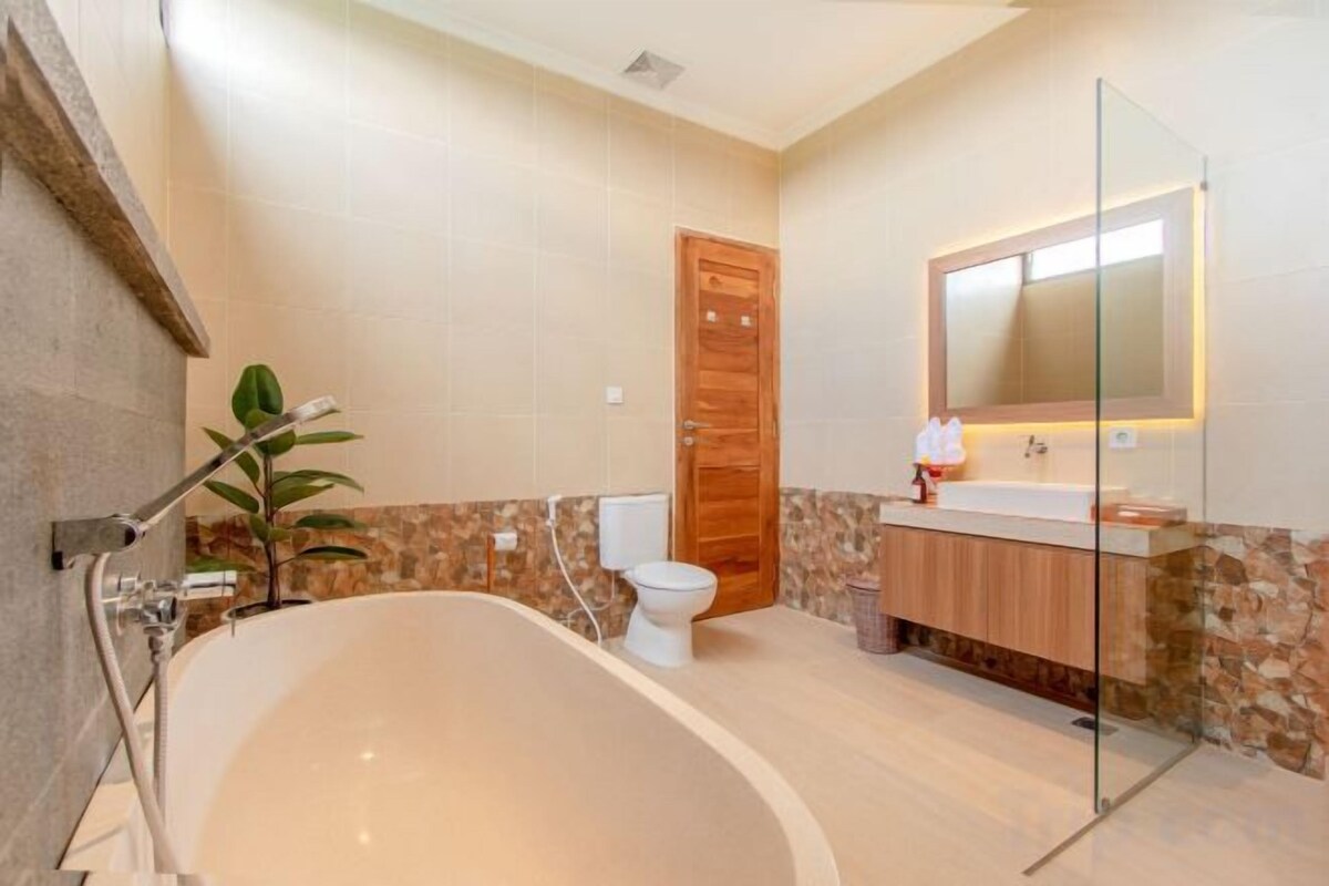 A modern bathroom with a freestanding bathtub, a toilet, and a vanity with a mirror.