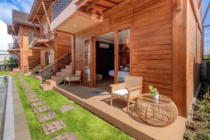 Une maison en bois dotée d’un patio, de meubles de jardin et d’un escalier menant à l’entrée.