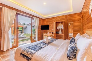 A spacious bedroom with a large bed, a television, a desk, and a wardrobe. - Anartha Resort Jimbaran By Kubu Gwk (Jimbaran)