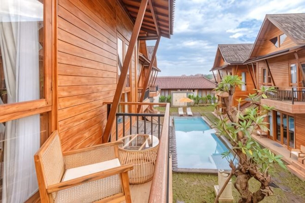 Een houten chalet met een balkon, een zwembadje en een tuin.