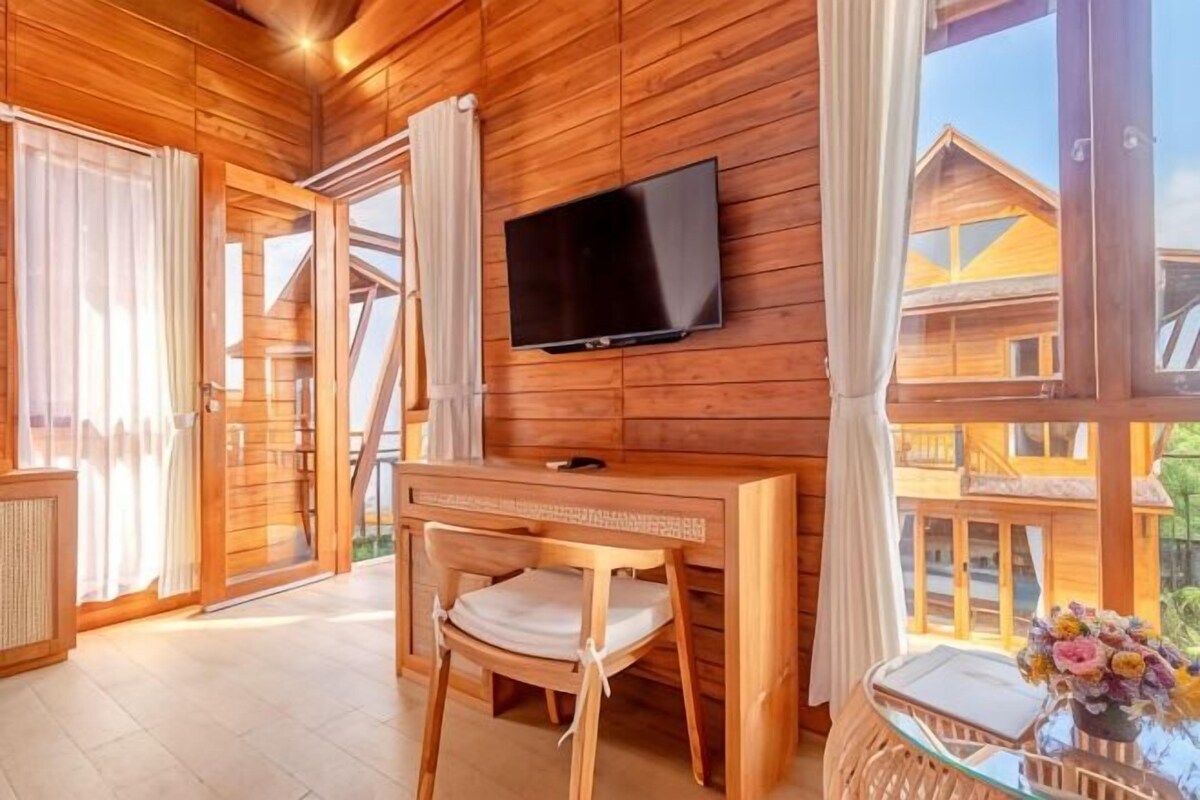 Un interior de madera con un televisor montado en la pared, un escritorio de madera y una silla.