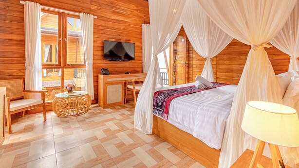 Een houten kamer met een bed, een televisie, een bureau en een stoel.