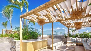 An outdoor patio with a wooden pergola, a built-in bar, and a seating area.