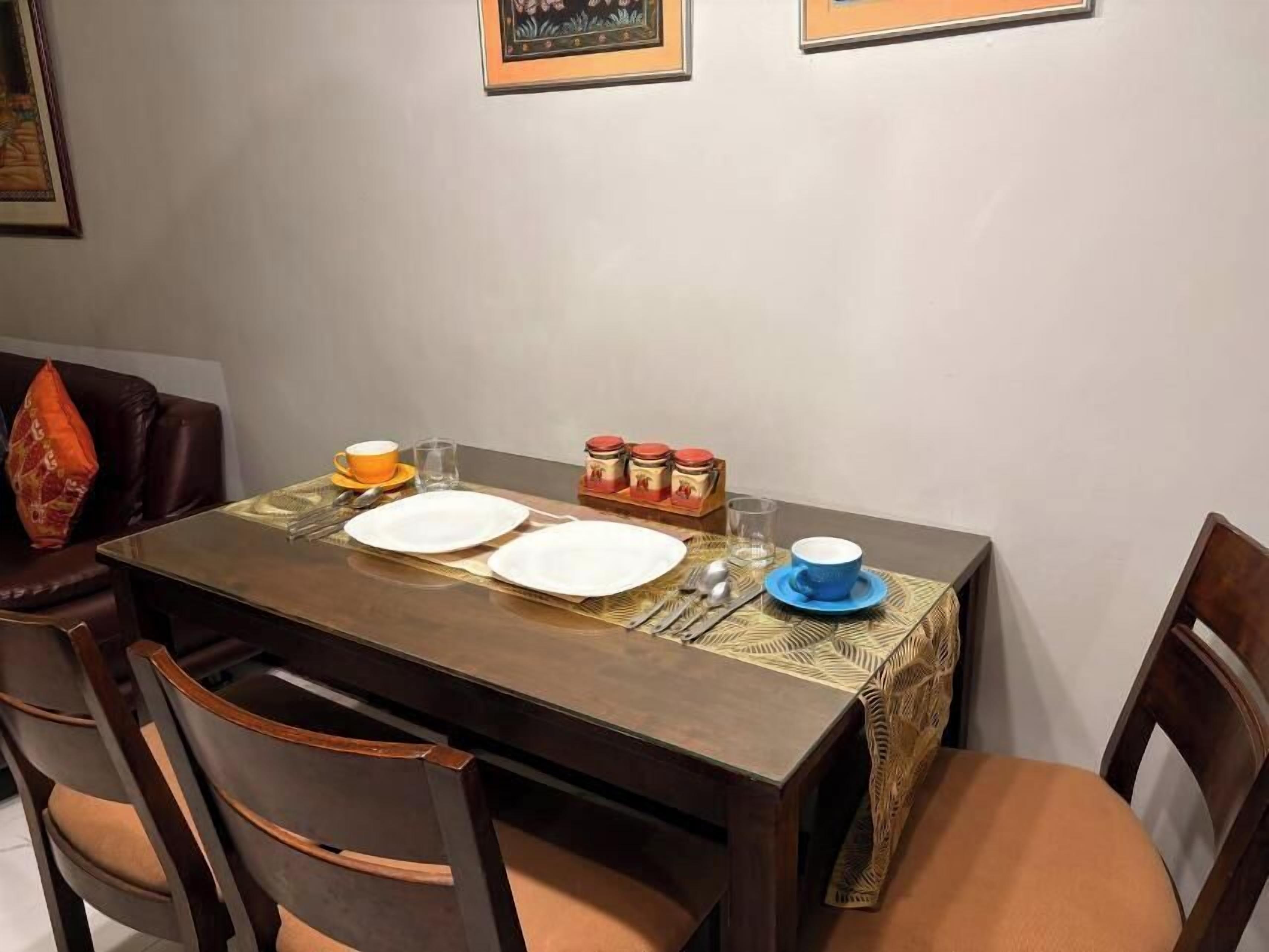A dining table set with plates, cutlery, and condiments, surrounded by chairs.