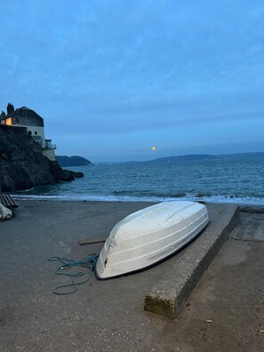 A boat on a concrete ledge by the sea with a building in the background.