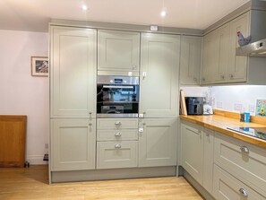 A kitchen with light-colored cabinets, a built-in oven, and a wooden countertop.