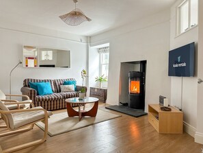 A modern living room with a sofa, armchairs, a coffee table, a fireplace, and a television.