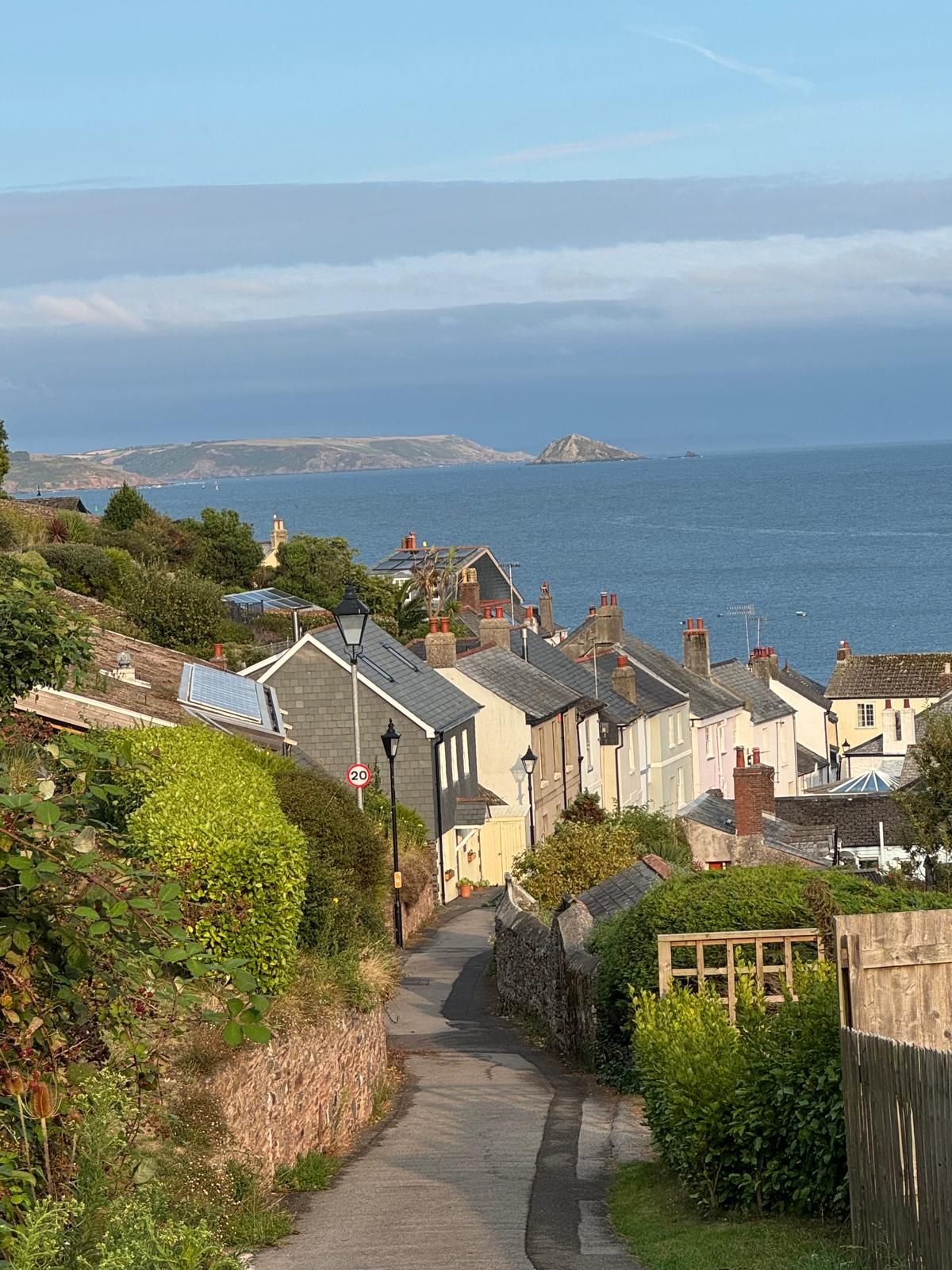 A coastal village with traditional houses, a narrow road, and a view of the sea.
