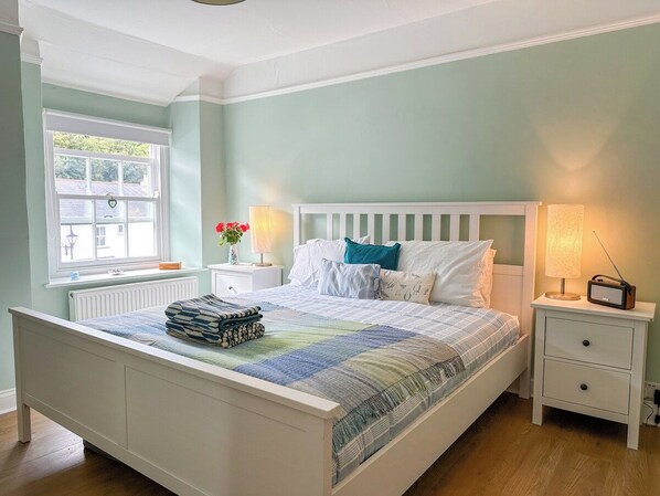 A bedroom with a bed, bedside tables, a window, and a lamp.