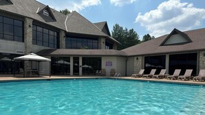 Ein Schwimmbecken mit Liegestühlen und einer überdachten Terrasse.