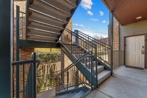 Un escalier menant à un balcon du deuxième étage, agrémenté d’une rambarde en métal, d’un mur en briques et d’une porte portant le numéro 9.