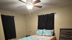 Una camera da letto con un letto, una ventola a soffitto, una cassettiera e un comodino.