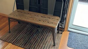 Una stanza con una panca in legno, un tappeto a righe e una panca di metallo appoggiata al muro.