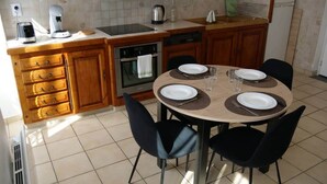 A kitchen with wooden cabinets, a stove, an oven, a sink, and a dining table set for four with chairs. - To complete (Bagnères-de-Bigorre)