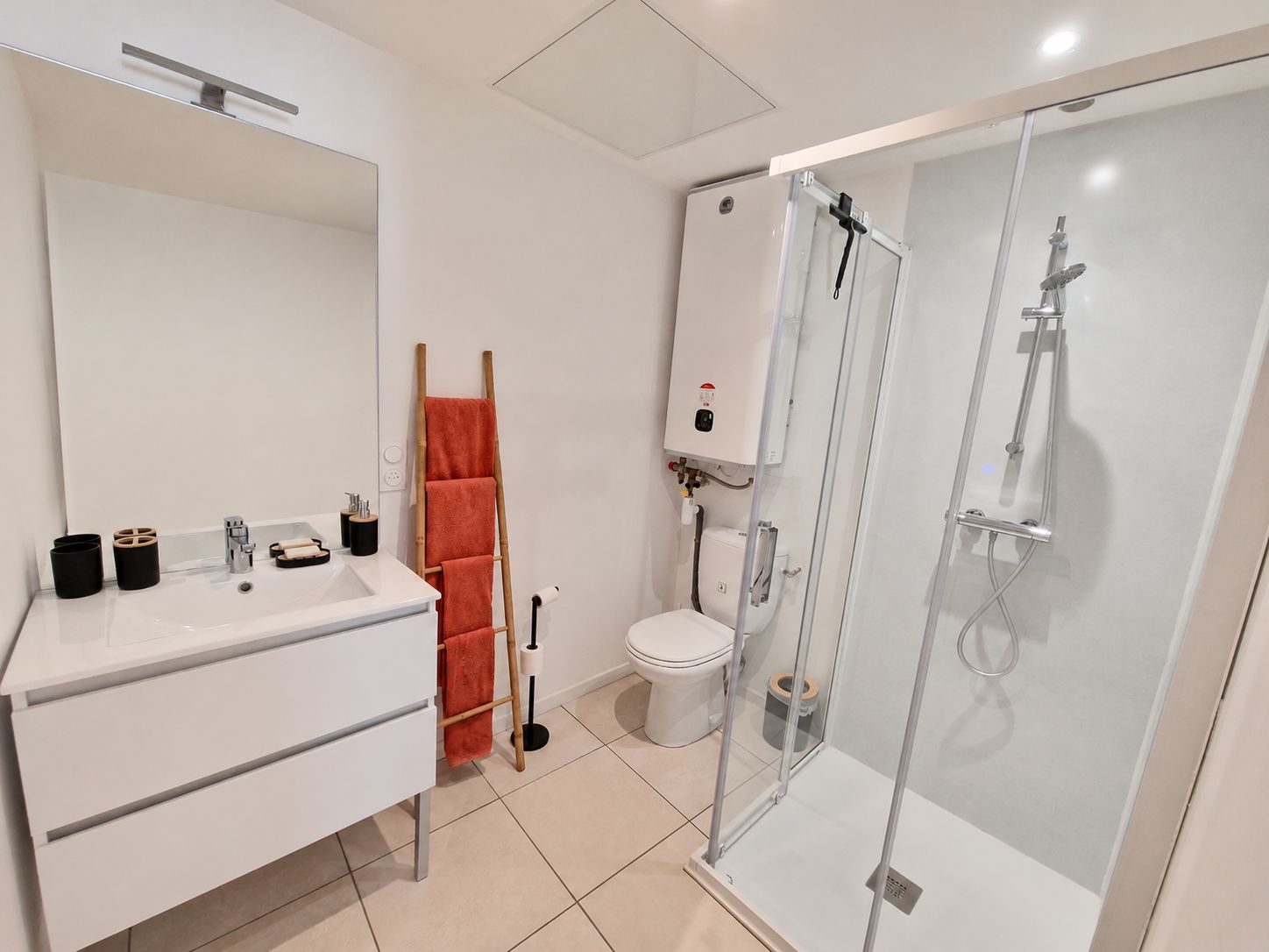 Une salle de bain moderne avec un meuble-lavabo blanc, une douche en verre et des toilettes.