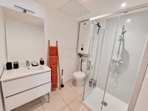 A modern bathroom with a white vanity, a glass shower enclosure, and a toilet.