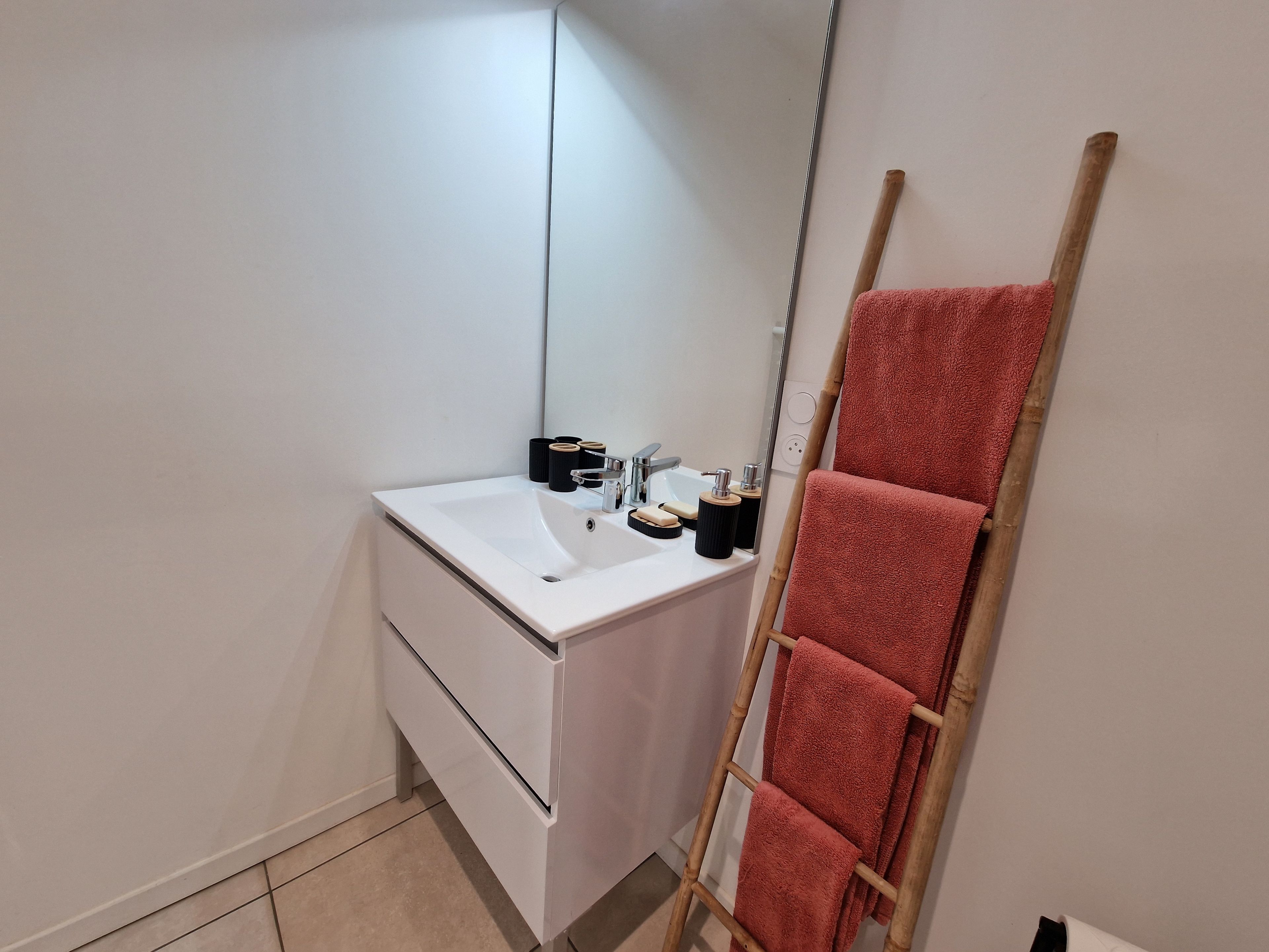 Een badkamer met een witte wastafel, spiegel en handdoekhouder.