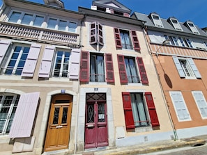 A multi-story building with distinct architectural features, including a variety of window styles and shutters, and a visible door with a number plaque. - To complete (Bagnères-de-Bigorre)