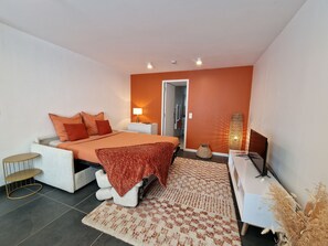 A modern bedroom with a bed, bedside table, lamp, and a large window.