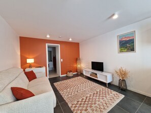 Un salon avec un canapé, un téléviseur et un tableau accroché au mur.