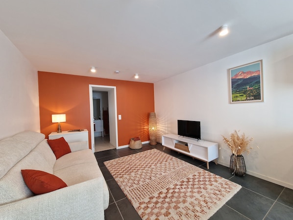 A living room with a sofa, TV, and a painting on the wall.