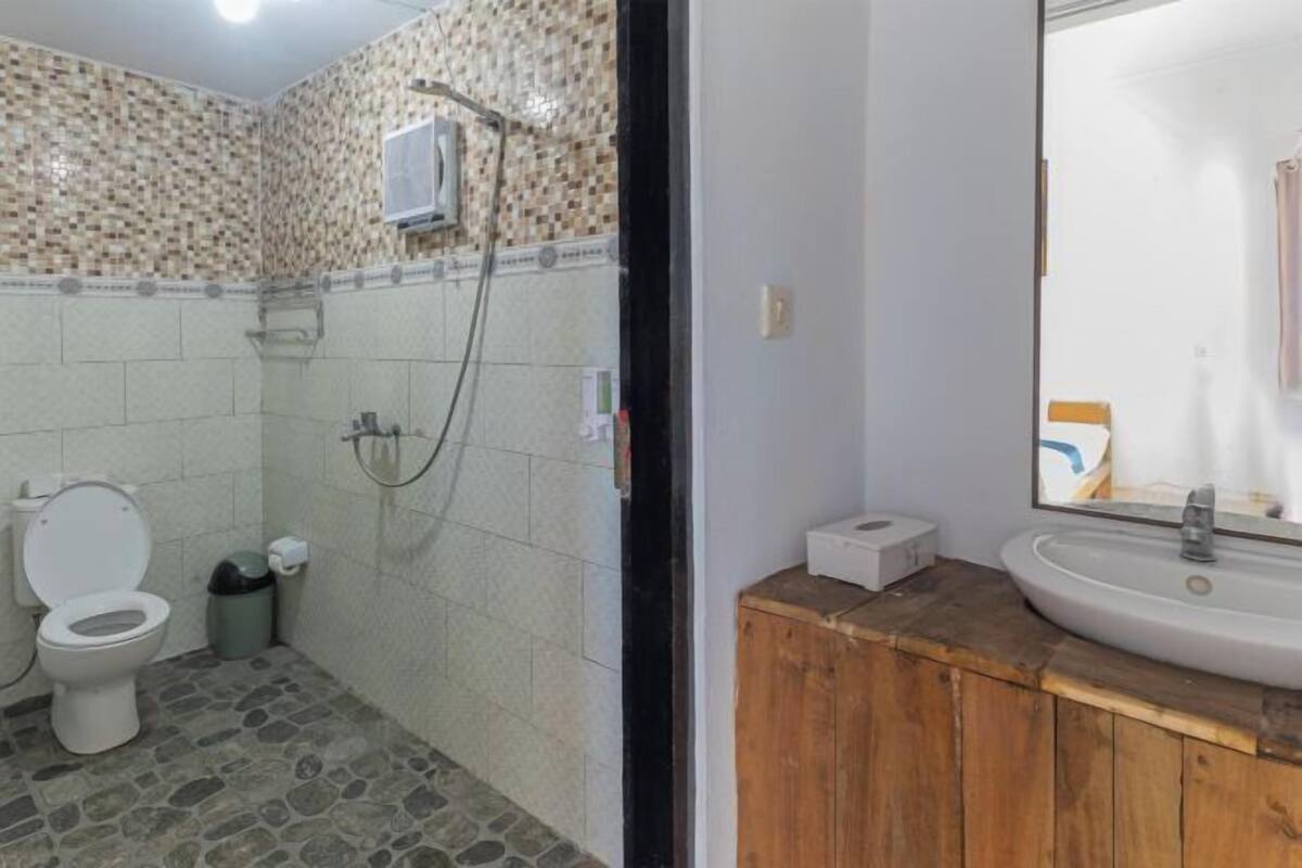 A bathroom with a toilet, shower, and sink.