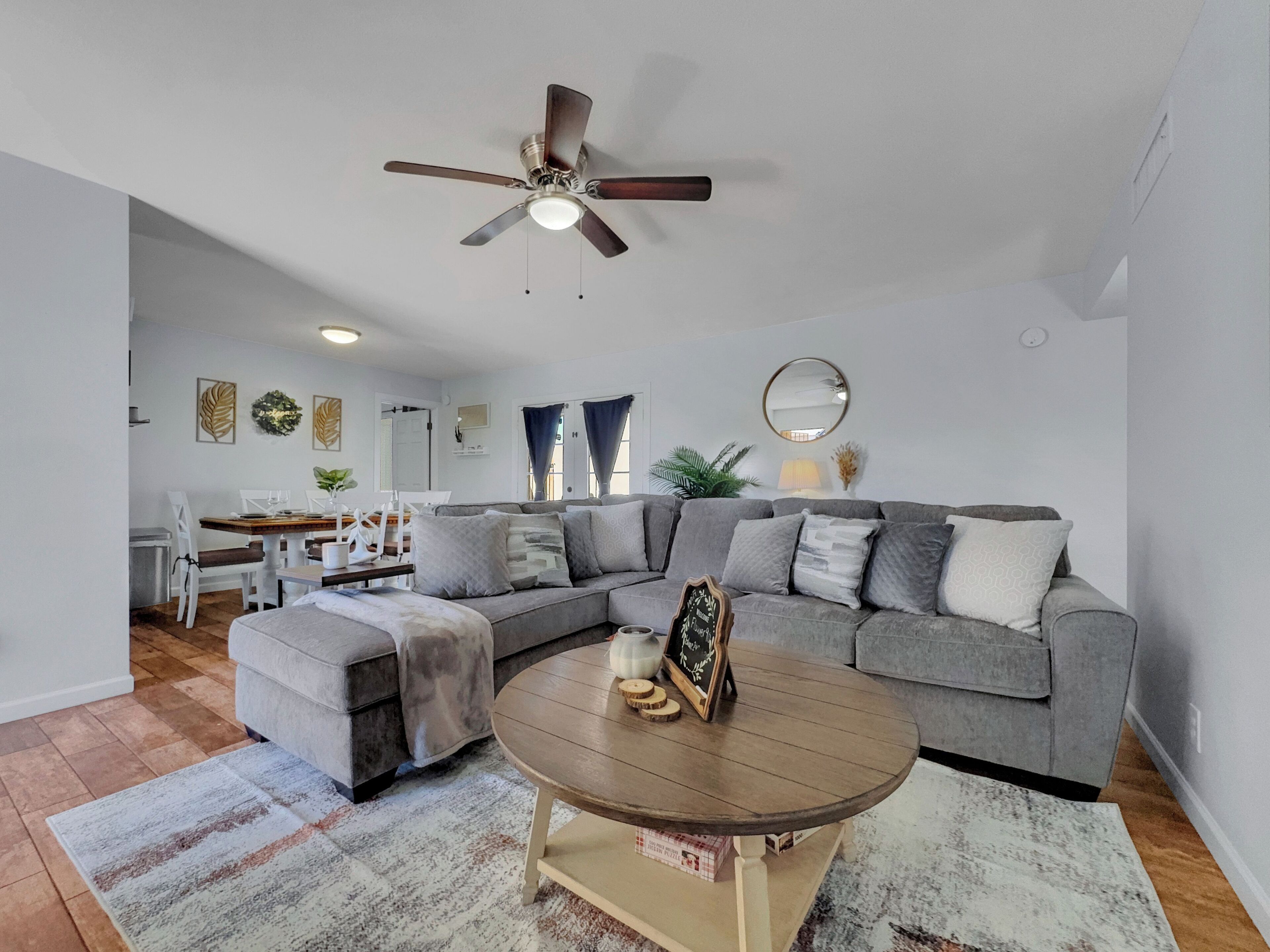 A modern living room with a sectional sofa, a round coffee table, and a ceiling fan.