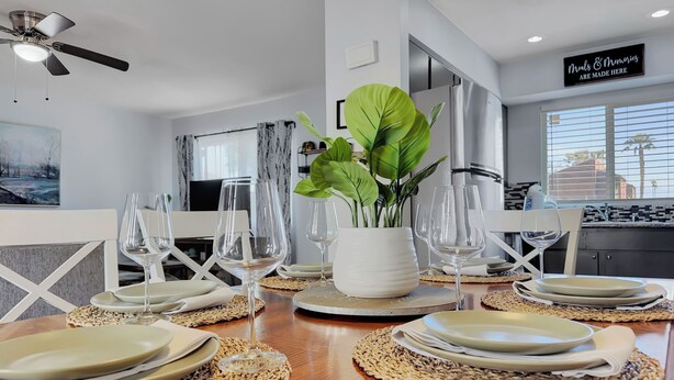 Un coin repas avec une table en bois dressée pour le repas, entourée de sets de table en fibres naturelles et de verres transparents.