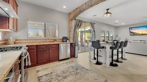 A modern kitchen with a gas stove, a dishwasher, and a dining area with a table and chairs. - Puesta Del Sol (Queen Creek)