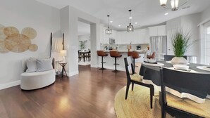 Una cocina moderna con armarios blancos, una isla central e iluminación colgante.