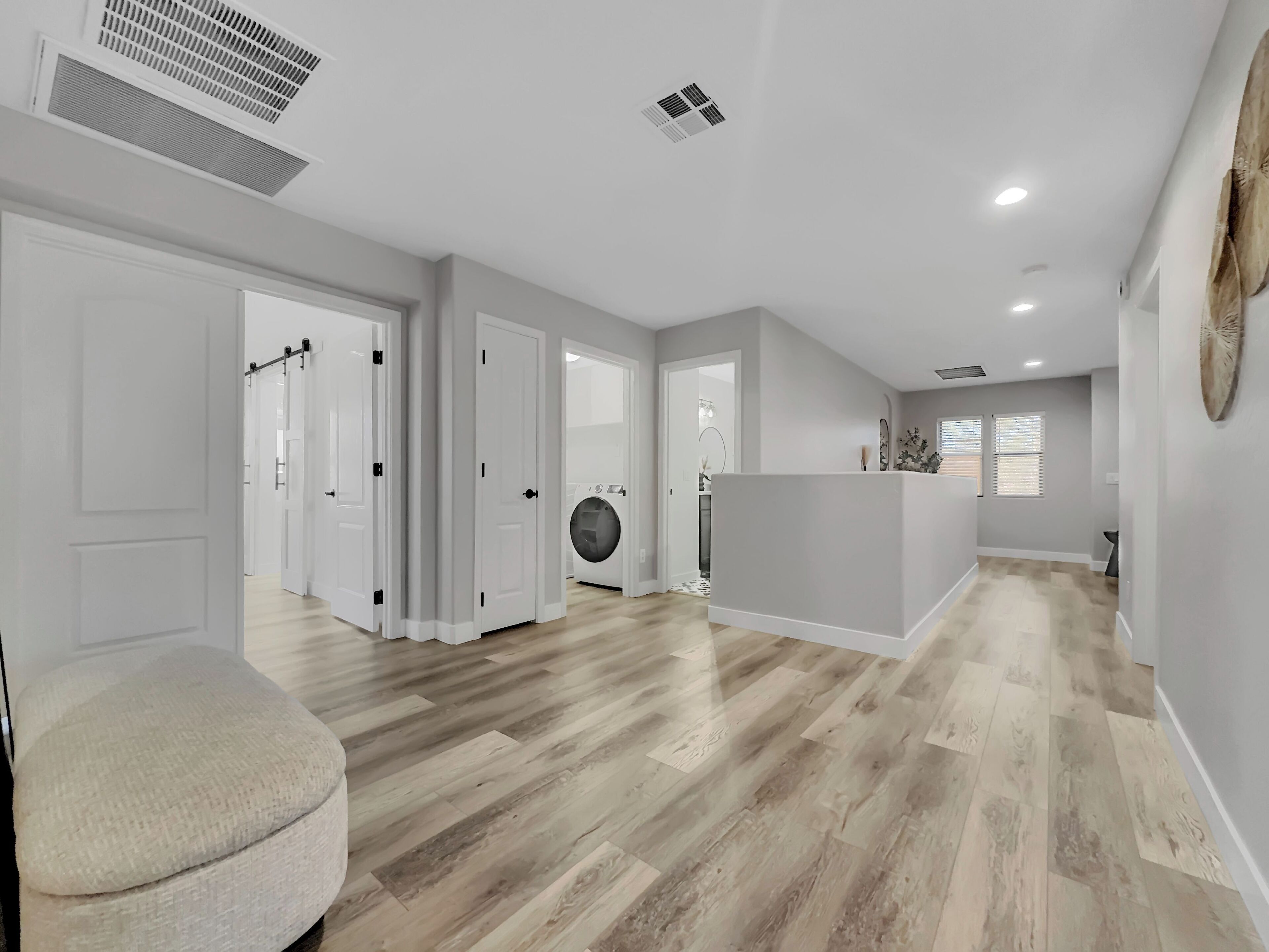 A spacious, modern interior with a central island, wooden flooring, and white walls.